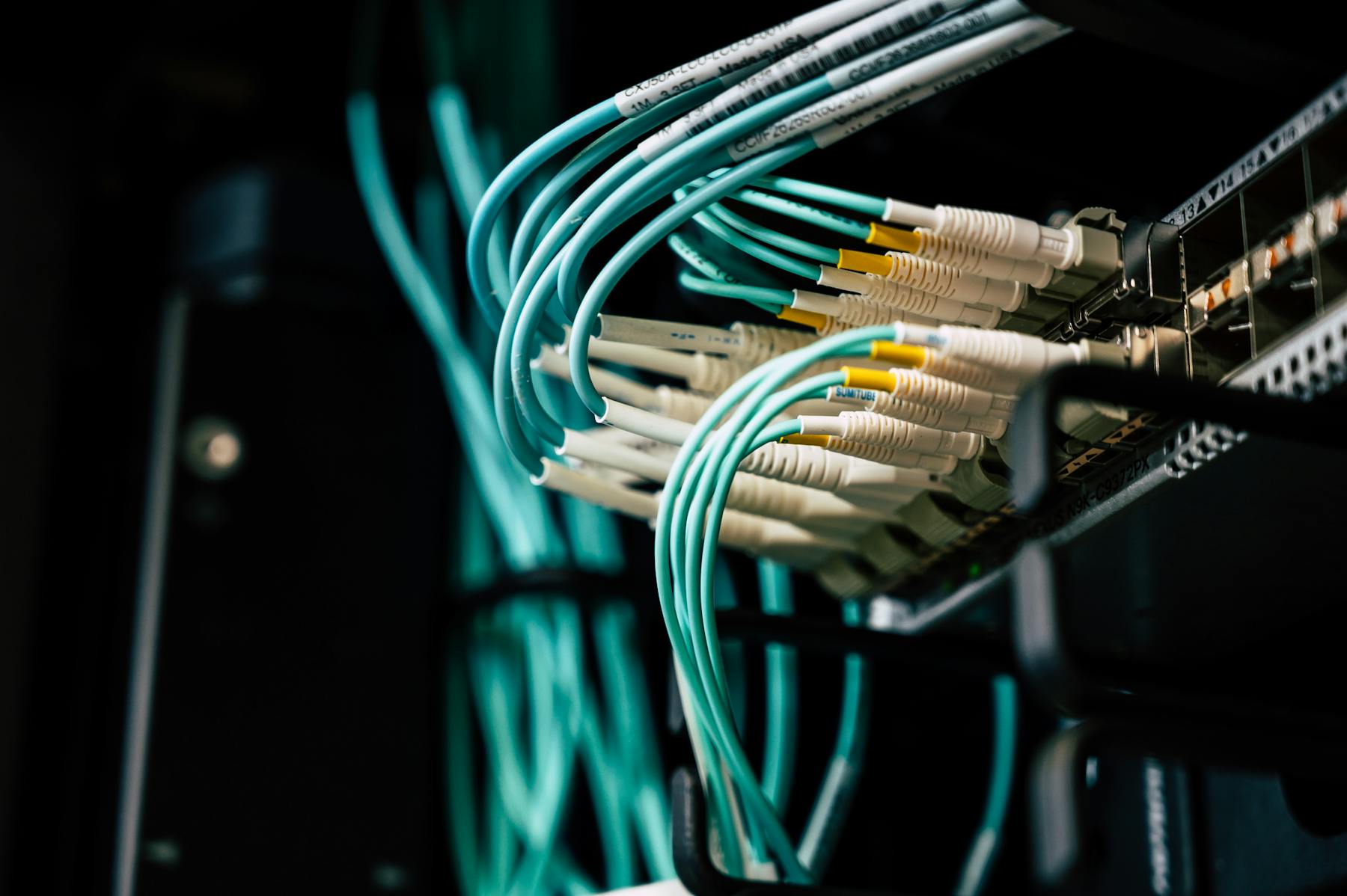 A technician's hand routing cables through a server rack